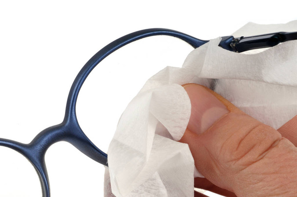 Limpiando sus gafas con una toallita óptica de cerca sobre un fondo blanco
 - Foto, Imagen