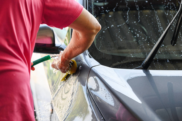 Worker washing and rubbing car with sponge and water - Photo, image