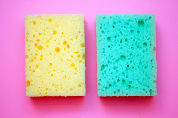 Green and yellow foam sponge for washing dishes. Soft washcloths on a pink background top view. - Photo, Image