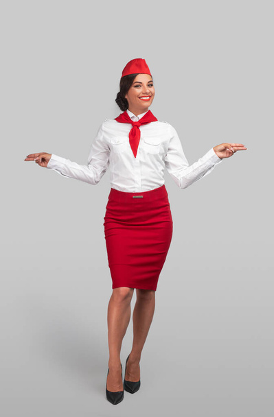 Cheerful flight attendant gesturing and smiling - Фото, изображение