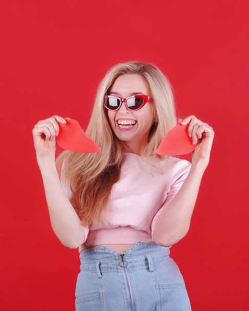 Young caucasian woman in sunglasses with broken red heart in hands. Valentine`s Day. Broken heart concept. - Фото, зображення