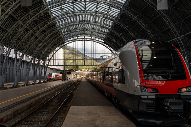 Treno in attesa alla stazione ferroviaria con vista panoramica sulle montagne sullo sfondo
 - Foto, immagini