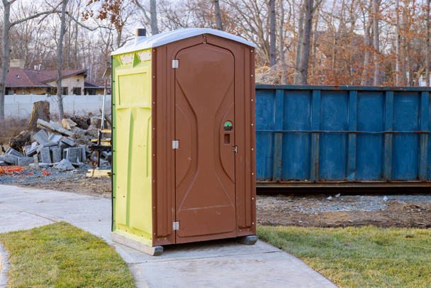 Toilettes portables sur la maison en construction dans une construction de benne à ordures avec poubelle nouvelle maison
 - Photo, image