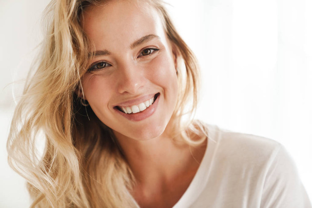 Smiling young beautiful blonde woman wearing t-shirt - 写真・画像