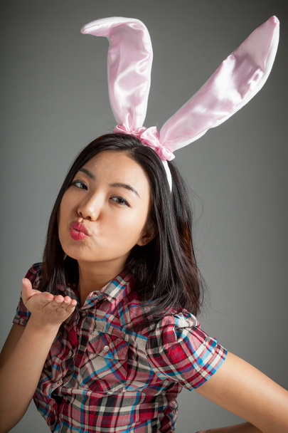 Portrait of sexy asian cowgirl wearing easter's bunny ears blowi - Фото, изображение