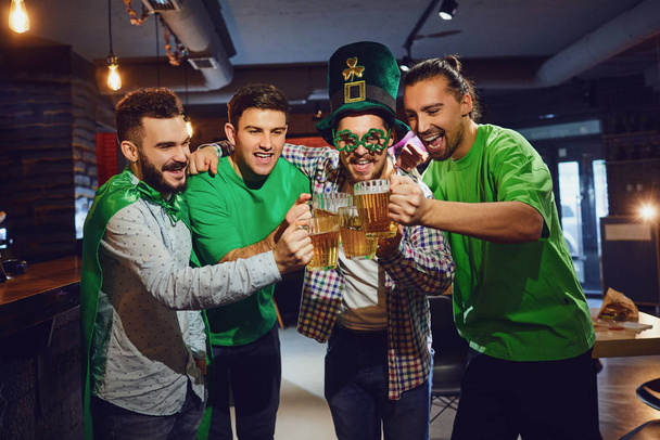Happy friends celebrating St. Patricks Day in a bar. - Фото, зображення