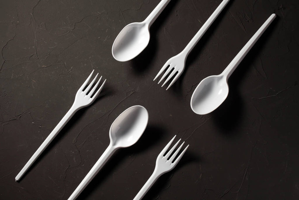 disposable fork and spoon on a dark background close-up - 写真・画像