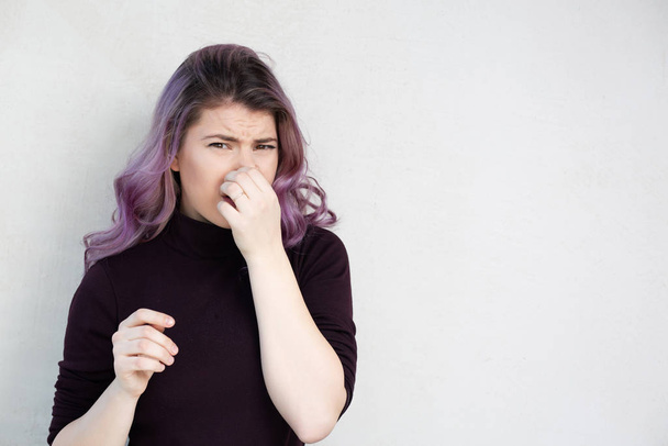 Aantrekkelijke vrouw houdt adem in met vingers op de neus - Foto, afbeelding
