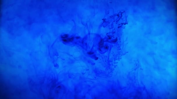 Blue color paint ink pouring over the glass with inky drops falling and abstract smoke explosion watercolors - Footage, Video