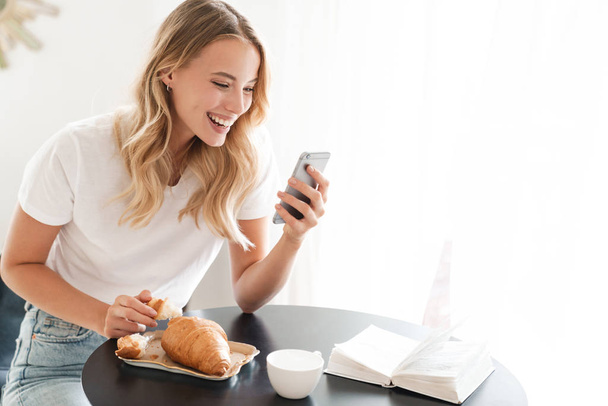 Houkutteleva nuori hymyilevä nainen käyttää matkapuhelinta
 - Valokuva, kuva