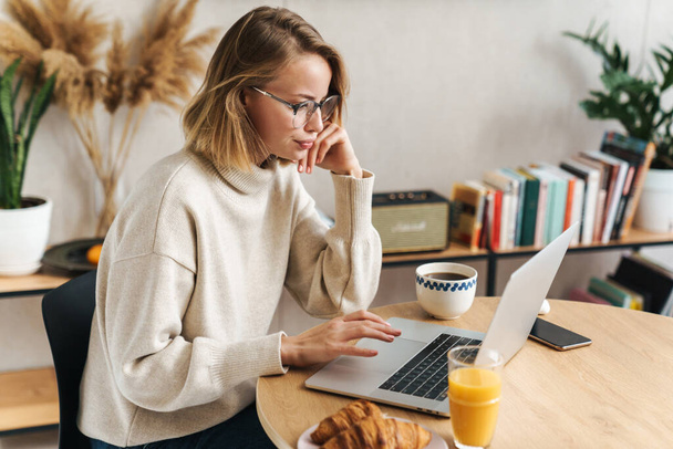 Photo of caucasian woman using laptop while having breakfast at  - Photo, image
