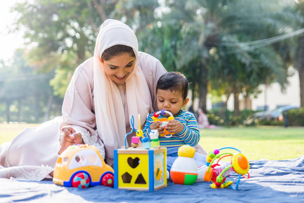 Arabic mom and her little toddler playing outdoors - Photo, Image