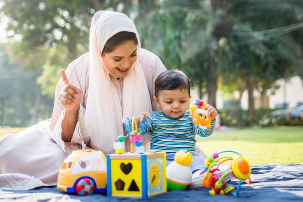 Arabic mom and her little toddler playing outdoors - Photo, Image