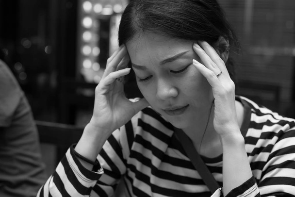 Hermosa mujer asiática tocó su templo con expresión dolorosa debido al sufrimiento de dolor de cabeza. Tono blanco y negro
 - Foto, imagen