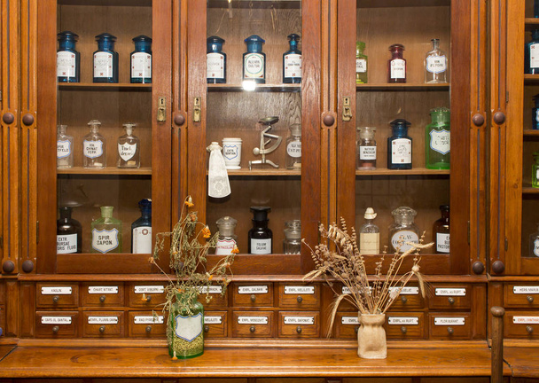 Erilaisia lääkepulloja säilytetään lasin takana myymälän ikkunassa vanhassa apteekissa.
 - Valokuva, kuva