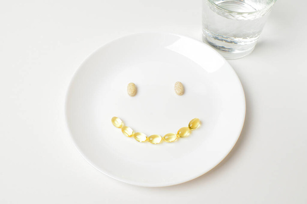 Πολυβιταμινούχο και ιχθυέλαιο κάψουλες σε σχήμα emoji χαμόγελο. - Φωτογραφία, εικόνα
