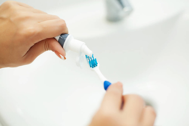 Nahaufnahme Hände Frau verwenden Zahnbürste im hellen Badezimmer - Foto, Bild