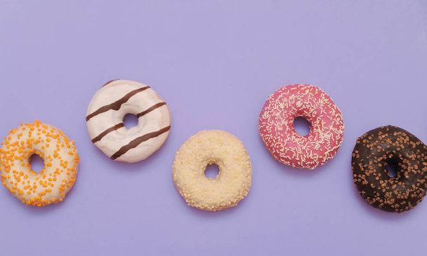 Delicious donuts on violet color background. - Photo, image