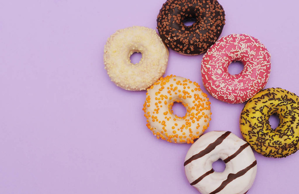 Delicious donuts on violet color background. - Foto, imagen