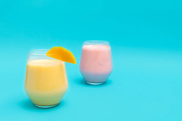 Bebidas de mango Lassi y fresa Lassi en vasos de vidrio sobre fondo azul
 - Foto, imagen