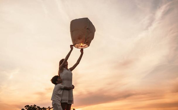Menina adolescente com o irmãozinho liberando lanterna céu
 - Foto, Imagem
