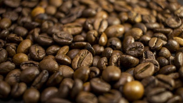 Dark background and texture of coffee beans, selective focus, closeup grains. - Photo, Image