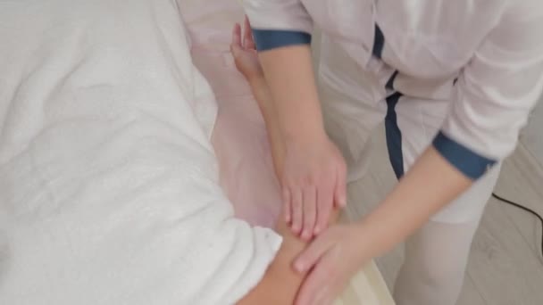 Woman massage therapist doing massage on the whole arm to a young girl in a massage parlor. - Imágenes, Vídeo