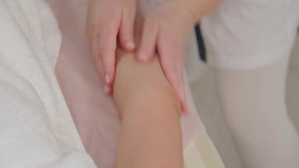 Woman massage therapist doing massage on the whole arm to a young girl in a massage parlor. - Filmagem, Vídeo