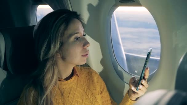 Gorgeous lady is using her phone while flying on the aircraft - Кадры, видео