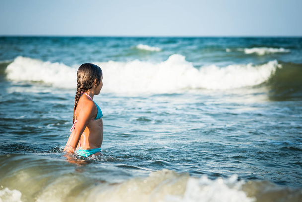 Happy emotional little girl bathes in sea waves - Fotoğraf, Görsel