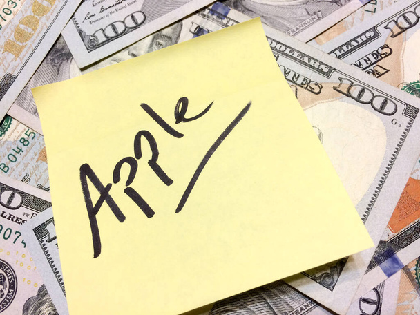 Dinero en efectivo estadounidense y papel amarillo con texto Apple
 - Foto, Imagen