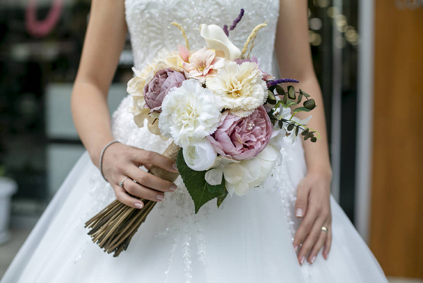 a noiva no vestido branco e um monte de flores em sua mão
 - Foto, Imagem