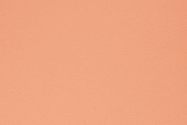 Peach colored paper. Delicate saturated background or wallpaper. Surface irregularities, spots and pores. View from above - Φωτογραφία, εικόνα