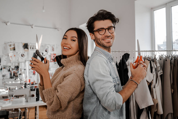 Teamwork. Scissors at the ready, like weapons in their hands, the main item in the life of a tailor. Design, studio for sewing and cutting clothes, designer clothes, manufacturing, craft product. - Foto, Bild