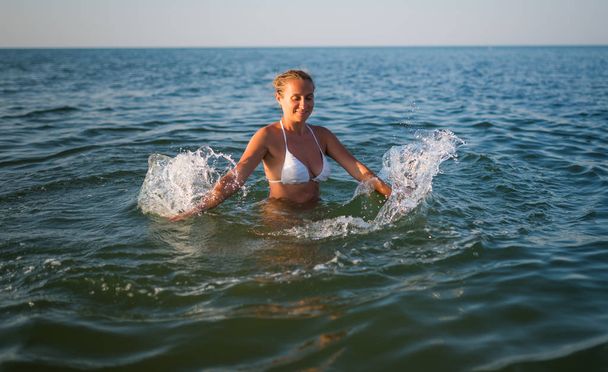 Rear view of pretty young woman swimming in sea - Foto, afbeelding