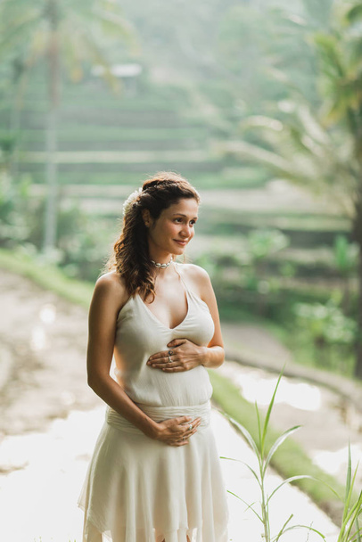 Young pregnant woman in white dress with view of Bali rice terra - Photo, Image