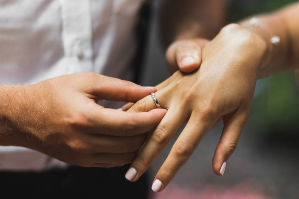 Man wearing wedding ring on woman hand close up. Symbol of love  - 写真・画像