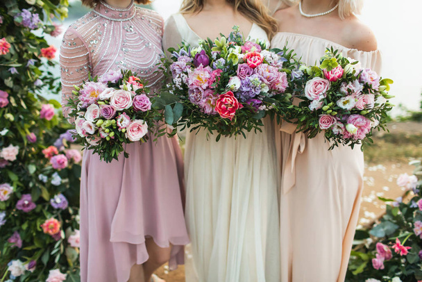 Три подружки нареченої тримають в руках красиві букети квітів
 - Фото, зображення