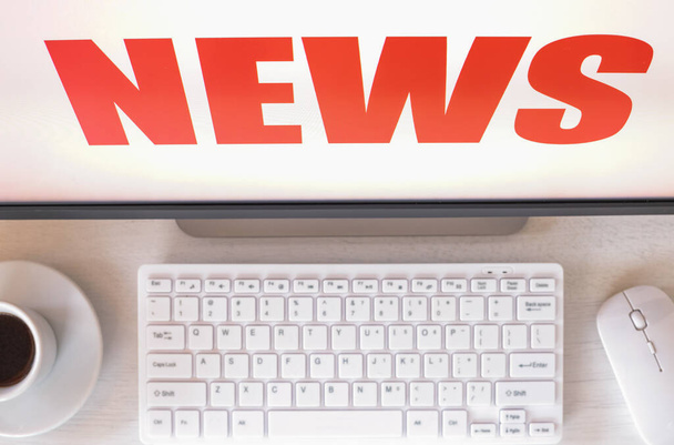 Computermonitor mit "News" -Text angezeigt Tastatur, Maus, Kaffee. Konzept, sensationelle Neuigkeiten, Event, Last Minute - Foto, Bild
