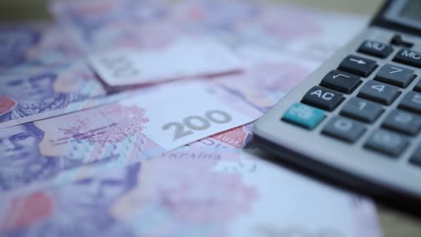 Uma dúzia de notas de moeda nacional ucraniana em câmera lenta estão caindo ao lado da calculadora
. - Filmagem, Vídeo