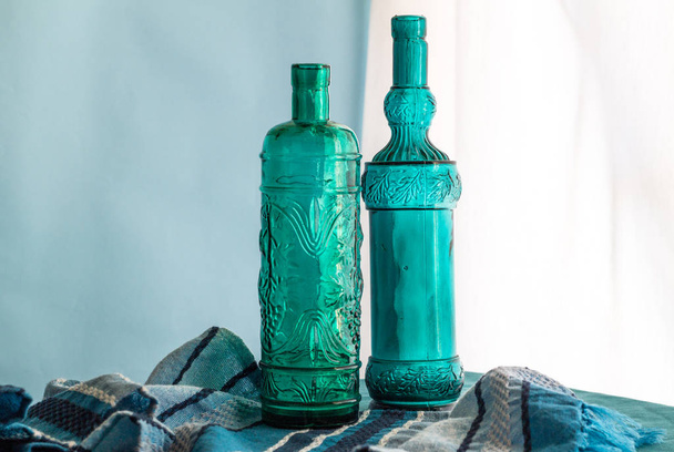 Still life with two hand crafted blue glass wine bottles made of recycled glass - Photo, Image