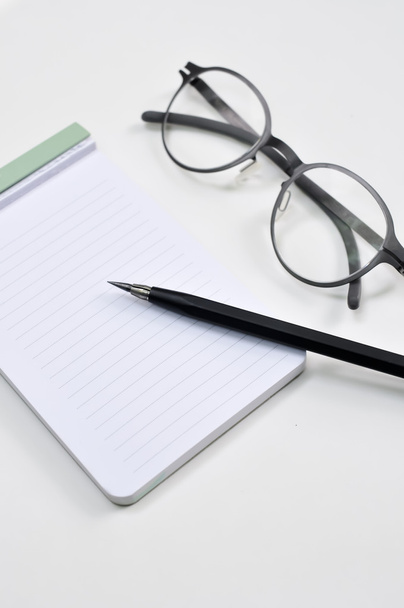 Óculos de olho, bloco de notas em branco e lápis mecânico na mesa
 - Foto, Imagem