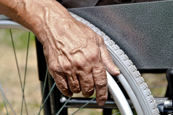 Een gehandicapte man zit in een rolstoel, houdt zijn handen op th - Foto, afbeelding