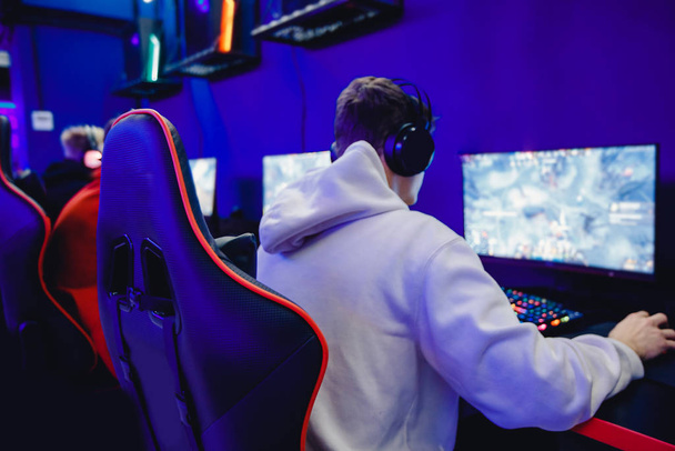 Επαγγελματίας gamer που παίζει τουρνουά σε απευθείας σύνδεση βίντεο παιχνίδια υπολογιστή με ακουστικά, κόκκινο και μπλε - Φωτογραφία, εικόνα