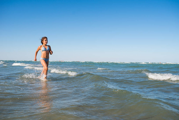 Πορτρέτο ενός χαρούμενου μικρού κοριτσιού που κολυμπάει στη θάλασσα - Φωτογραφία, εικόνα