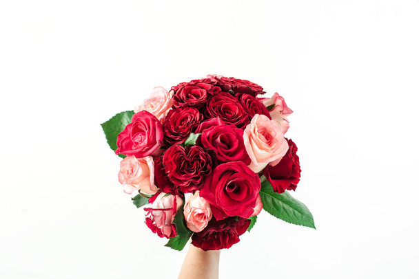 Růžové a červené květy růže kytice v ruce ženy na bílém pozadí. Dovolená, dárek k Valentýnu. - Fotografie, Obrázek