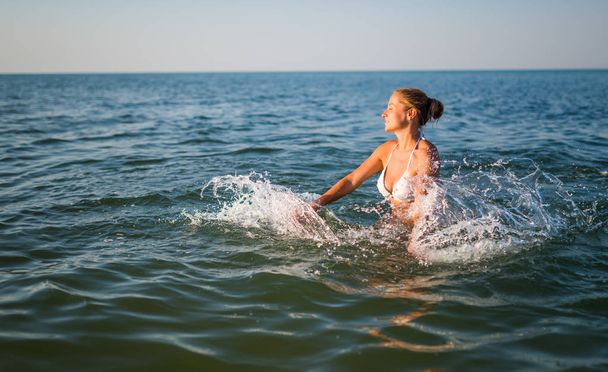 Rear view of pretty young woman swimming in sea - Foto, Imagen