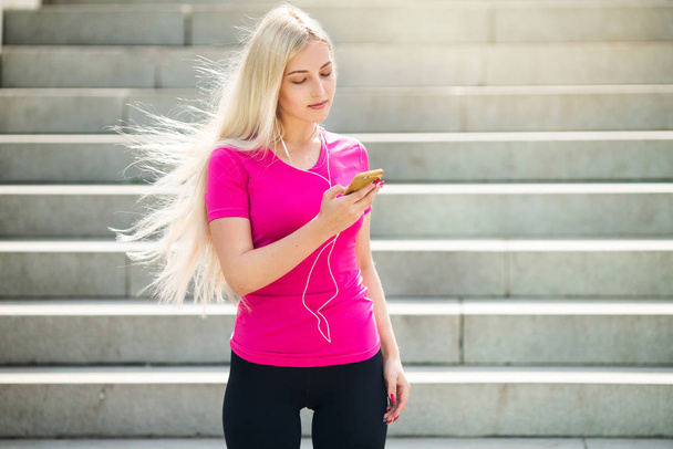 beautiful young woman in sportswear with her hair with a phone in her hand - Zdjęcie, obraz