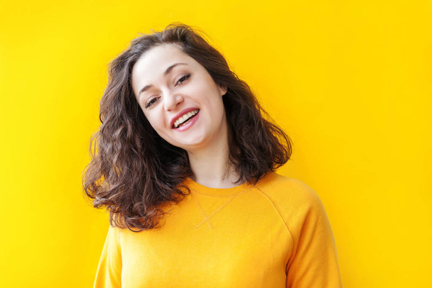 Chica feliz sonriendo. Retrato de belleza joven feliz positivo riendo morena mujer sobre fondo amarillo aislado. Mujer europea. Emoción humana positiva expresión facial lenguaje corporal
 - Foto, imagen