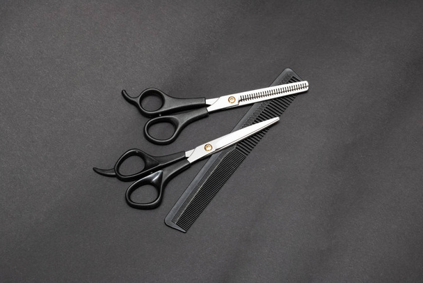 Парикмахерские ножницы и расческа на сером фоне
 - Фото, изображение